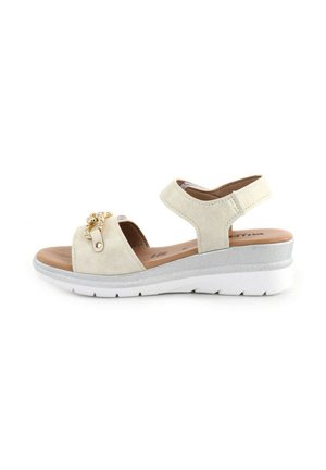Sandal beige con tomaia in suede, cinturino regolabile e accentuazione decorativa in catena dorata. Caratterizzata da una suola bianca antiscivolo con un bordo argentato.