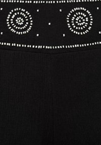 Black fabric with textured surface. Features white bead-like embellishments arranged in circular and linear patterns.