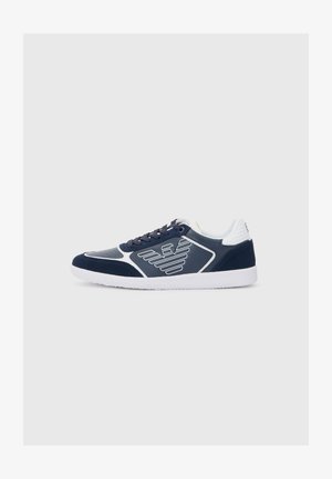 Mornarsko modri športni copati z belimi detajli, ki vključujejo teksturirano blago, gladke panele, perforacije in logotipne detajle na straneh.