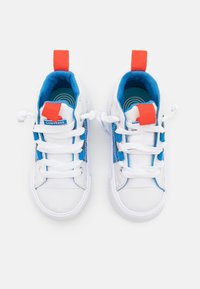 Weiße Leinensneaker mit blauen Akzenten, ausgestattet mit zwei roten Zuglaschen, weißen Schnürsenkeln und einer strukturierten Außensohle. Converse-Logo auf der Zunge.