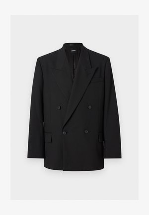 Blazer noir pour homme à double boutonnage avec revers à pointe, quatre boutons, poches à rabat et une poche poitrine passepoilée, présenté sur fond blanc.