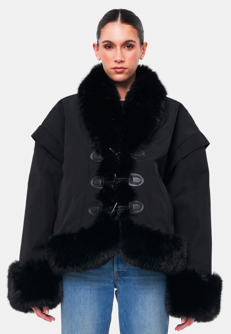 Giacca nera oversize con colletto e polsini in pelliccia sintetica, dotata di chiusure a bottone e tessuto texture. Design durevole e caldo.