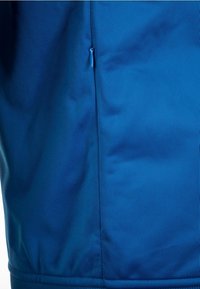 Blå atletisk klädnad med en slät tygtextur, en liten dragkedjeficka på sidan och en figurnära design vid fållen.