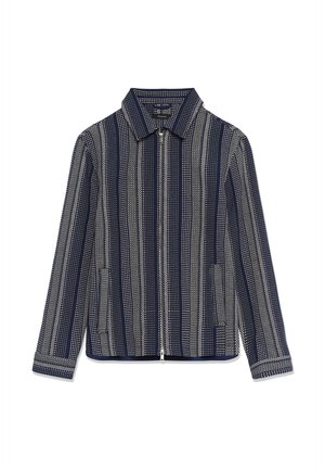 Chaqueta azul marino con rayas blancas verticales de puntos, cierre frontal con cremallera, dos bolsillos laterales y cuello puntiagudo.