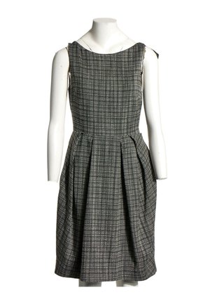 Robe sans manches longueur genoux avec motif à carreaux noir et blanc, corsage ajusté et jupe plissée, présentée sur un mannequin blanc.