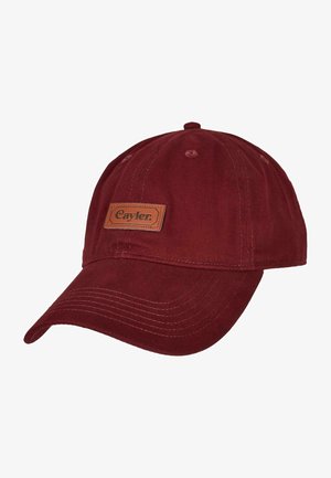 Bordeaux katoenen pet met een gebogen rand, voorzien van een bruine leren patch met het label "Cayler." Zichtbare stiksels en oogjes voor ventilatie.
