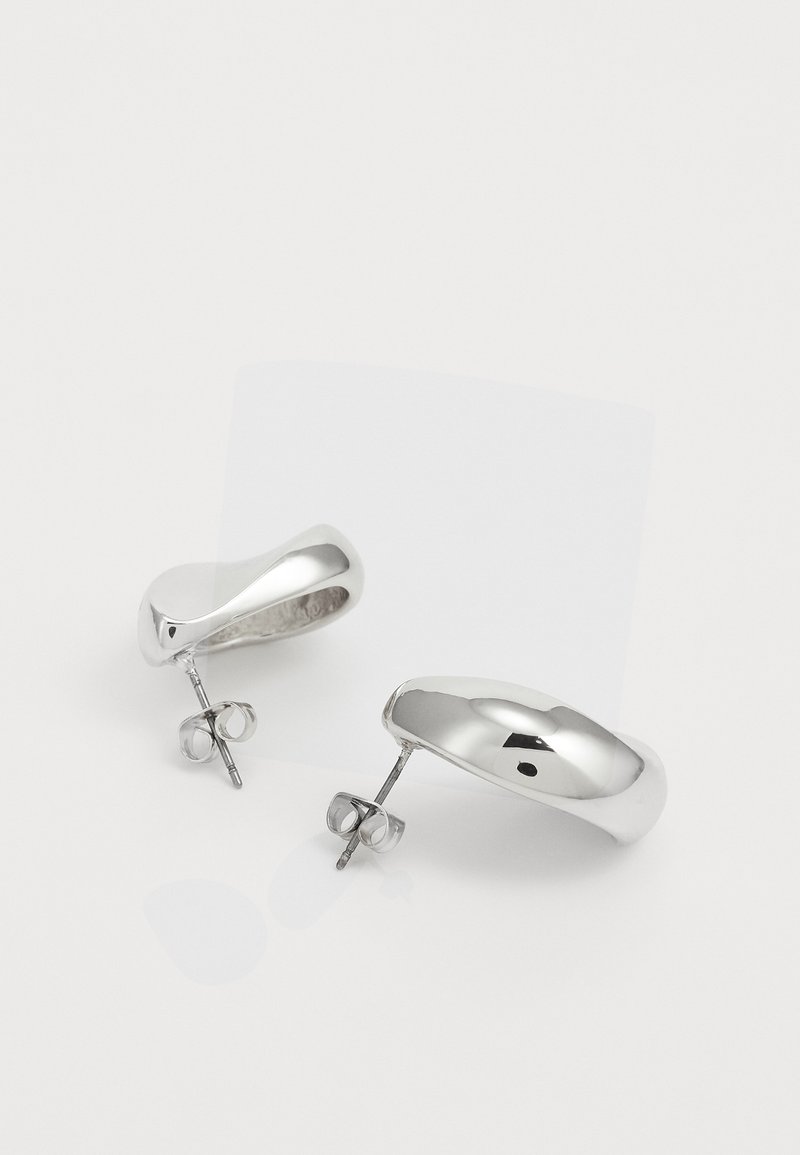 Boucles d'oreilles en argent avec un design lisse et arrondi et une surface polie. Comprend un fermoir sécurisé pour un port facile et confortable.