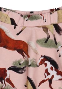 Rosa Stoff mit einem Muster von galoppierenden Pferden in verschiedenen Farben, akzentuiert mit grünem Gras. Das Material hat eine glatte Textur.