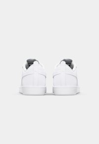 Vita sneakers med en slät läderfinish, vadderad krage, texturerad häl och kontrasterande grå insida. Minimalistisk design med logotypdetalj.