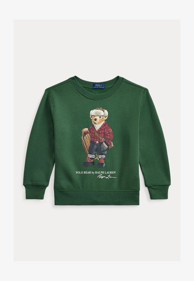 Grønn genser med en bjørn i rutete antrekk, med grafiske detaljer og ribbede mansjetter. Logotekst nederst, avslappet design.