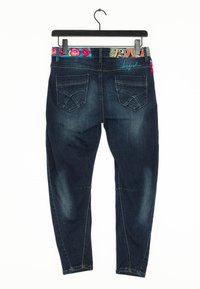 Jeans de mezclilla azul oscuro con una cinturilla de patrón colorido. Las características incluyen dos bolsillos traseros y detalles de costura a lo largo de las piernas.