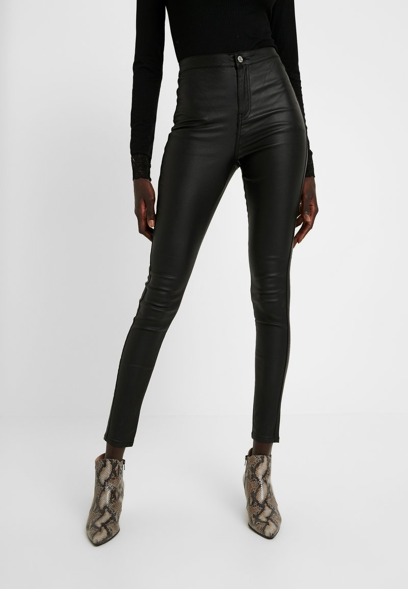 Svarta högmidjade byxor i konstläder med en smal passform, med en knappstängning fram och subtil lyster. Bärs med ankelboots i ormskinn.