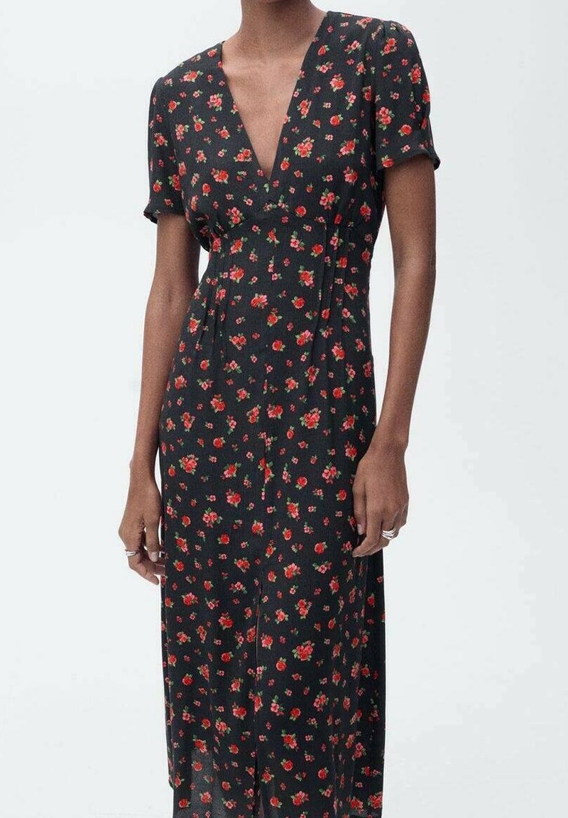 Femme portant une robe midi noire à manches courtes avec un imprimé floral rouge, dotée d'un col en V et d'une taille cintrée.