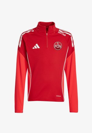 Rød langærmet Adidas sportstop med 1. FCN klublogo, hvide striber på skuldrene, halv lynlåskrave og teksten "Der Club" nær kraven.