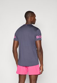 Jūras spēku sporta krekls ar rozā akcentiem, īsām piedurknēm un apaļu kakla izgriezumu. Uz piedurknēm teksts "BOBG". Gluda, viegla auduma.