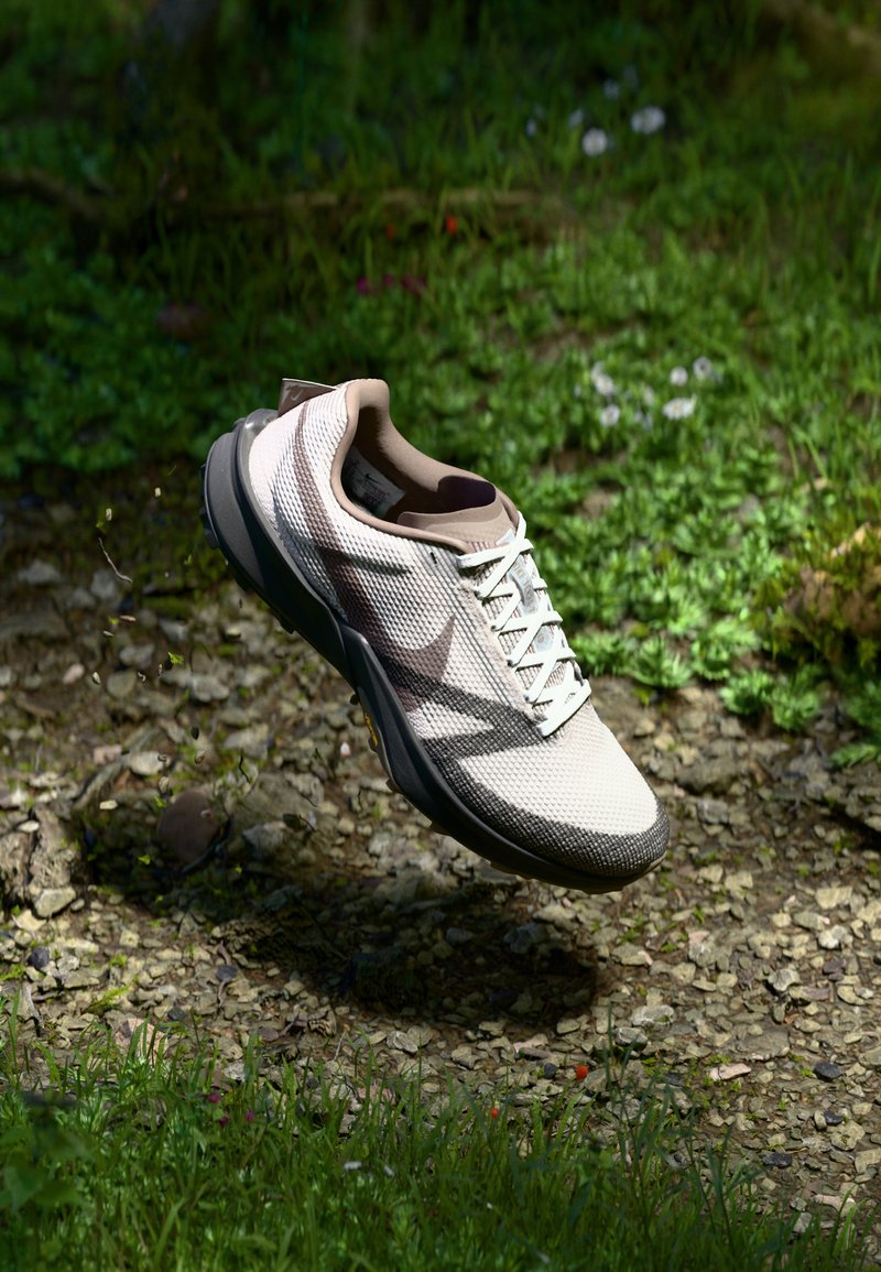 Chaussure de sport légère avec une tige en mesh blanc texturé et respirant, des accents marron et une semelle grise, dotée de lacets contrastants.