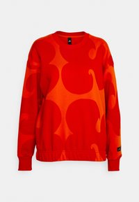 Sweat-shirt rouge avec de grands motifs abstraits ondulés dans différentes nuances de rouge et d'orange. Dispose d'un col côtelé et d'un ourlet élastiqué.