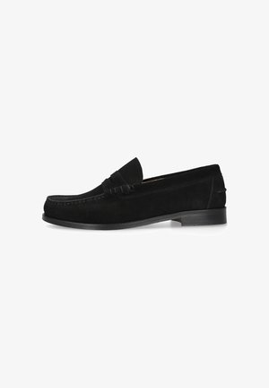 Zwarte suède herenloafer met een lage hak, mocassinnaad en een riemdetail over het bovenwerk, zijaanzicht tegen een witte achtergrond.