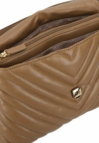 Sac à main en cuir matelassé marron avec un motif texturé, une quincaillerie dorée et une poche intérieure zippée. Finition lisse et forme arrondie.