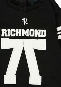 Felpa nera con scritta bianca "RICHMOND" e numeri oversize "77" sul davanti. Girocollo a costine e dettagli a righe sulle maniche.