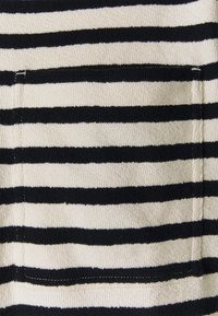 Tissu à rayures horizontales noires et blanches avec une poche rectangulaire cousue sur la surface.