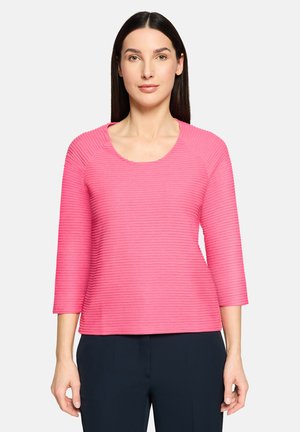 Różowy prążkowany top z dekoltem w łódkę i rękawami do połowy przedramienia. Gładka faktura z pionowymi paskami, dopasowany krój.