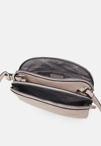 Borsa a tracolla beige trapuntata con due scomparti con zip; esterno liscio, l'interno presenta una fodera decorata, tracolla regolabile.