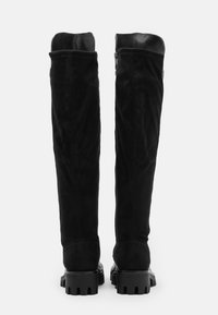 Stivali neri sopra il ginocchio in suede con dettagli in pelle liscia, dotati di una suola in gomma testurizzata e pesante e una cerniera laterale.