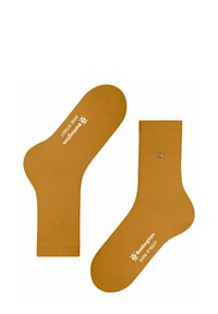 Calzini a coste giallo senape realizzati in materiale morbido, con marchio stampato bianco e un accent metallico su uno dei calzini.