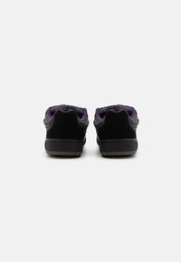 Adidași negri din suede, cu un superior din plasă gri texturată și accente mov. Dispun de un guler căptușit și o talpă din cauciuc maro în contrast.