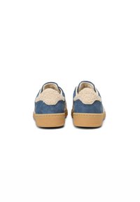 Niebieskie zamszowe buty z teksturowanym beżowym materiałem na tylnej części oraz jasnobrązową gumową podeszwą. Zaokrąglony czubek i casualowy design.