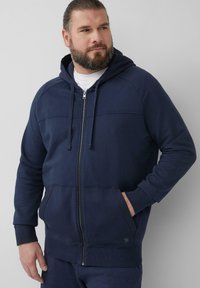 Marineblauer Reißverschluss-Hoodie mit Kapuze und Kordelzug, Fronttaschen und gerippten Bündchen. Weiches Material mit glatter Textur und minimalistischem Design.