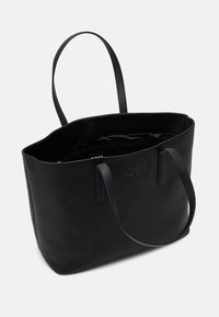 Czarna skórzana torba typu tote z dwoma uchwytami, wytłoczone logo "BOSS" z przodu, oraz zamykana kieszeń wewnętrzna, pokazana otwarta na tle białym.