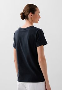 Black cotton t-shirt with short sleeves, round neckline, and relaxed fit; smooth texture with subtle stitching details at the collar.