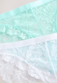 Du poros nėrinių apatinio trikotažo: vienas šviesiai mėtos spalvos su gėlių raštais, kitas baltos spalvos, abu su minkštu elastiniu liemeniu.