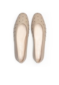 Bailarinas beige hechas de material sintético suave, con una punta redonda y tachuelas negras decorativas en la parte superior.