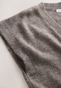 Gray knit sweater with a v-neck design, textured fabric, ribbed neckline, and short sleeves. Soft, warm appearance with a subtle pattern.