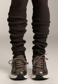 Ciorapi de picior tricotati, de culoare maro, cu o textur�ă ribbed, design lejer, asortați cu adidași sport de nuanțe închise, cu accente din plasă și patent.
