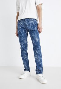 Lett blå denim jeans med et sky-lignende teksturmønster, rett bensdesign og klassisk fem-lomme styling, kombinert med hvite joggesko.