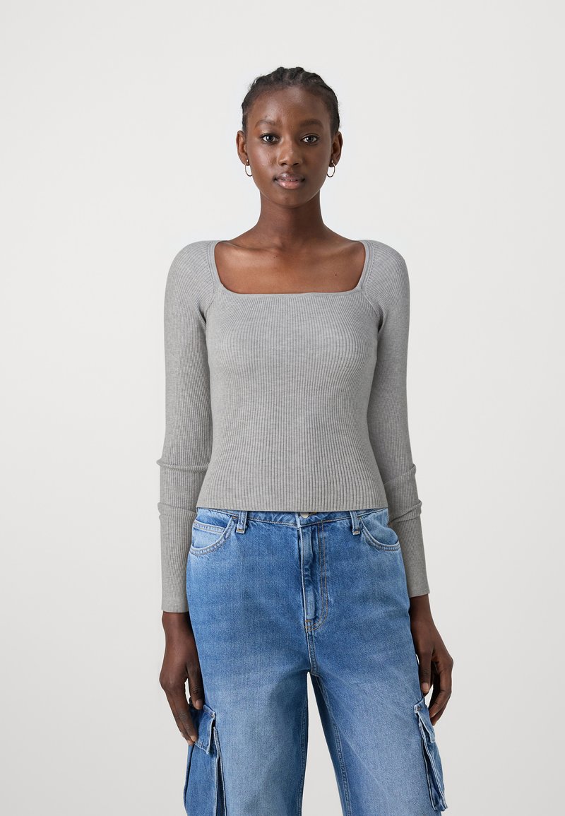 Haut à manches longues gris côtelé avec un décolleté carré, associé à un jean cargo bleu clair avec poches latérales et une coupe décontractée.