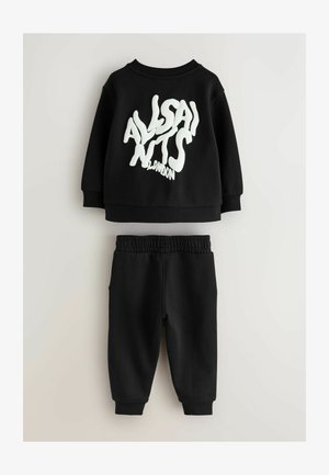 Schwarzes Sweatshirt- und Hosen-Set mit einem großen weißen Textgrafik auf der Vorderseite. Weicher Stoff, lockere Passform, elastischer Bund und Bündchen.