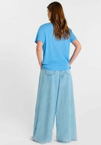 Lichtblauw oversized T-shirt met korte mouwen, gecombineerd met lichtblauwe denim broek met wijde pijpen, met een losse pasvorm en zachte textuur.