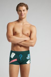 Boxers verdes ajustados con gráficos temáticos del juego Monopoly, que incluyen signos de interrogación y varias cartas. Textura de tela suave.