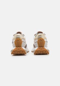 Adidași albi și bej cu accente maro, țesătură texturată, talpă groasă și modele de profil îndrăznețe. Prezintă logo-ul la călcâi.