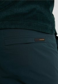 Mörkt havsblå byxor i slät tyg med slim fit. Har ett bakfack och en läderetikett med märket "CHASIN'."