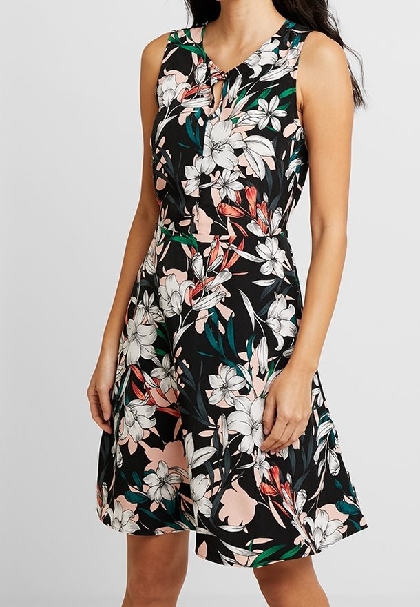 Květinové šaty bez rukávů v černé barvě s bílými, růžovými a zelenými vzory; mají výstřih do V a stažený pas vedoucí k rozšířené sukni.