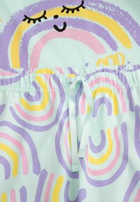 Miękka tkanina w kolorowe abstrakcyjne tęcze w pastelowych odcieniach różu, żółci i fioletu, z uśmiechniętą buzią z zamkniętymi oczami i sznurkiem w pasie.