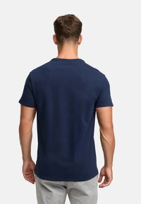 Granatowa koszulka z krótkim rękawem z okrągłym dekoltem, o gładkiej bawełnianej fakturze i luźnym kroju. Bez widocznych wzorów ani grafik.