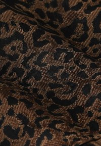 Tissu imprimé léopard présentant un motif texturé et tissé dans des nuances de noir et de bronze, créant un contraste audacieux et une surface tactile.