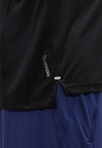 Μαύρο αθλητικό πουκάμισο με ετικέτα "Climacool" και οπές αερισμού σε συνδυασμό με μπλε αθλητικό σορτς με ραμμένες ραφές και τσέπη.